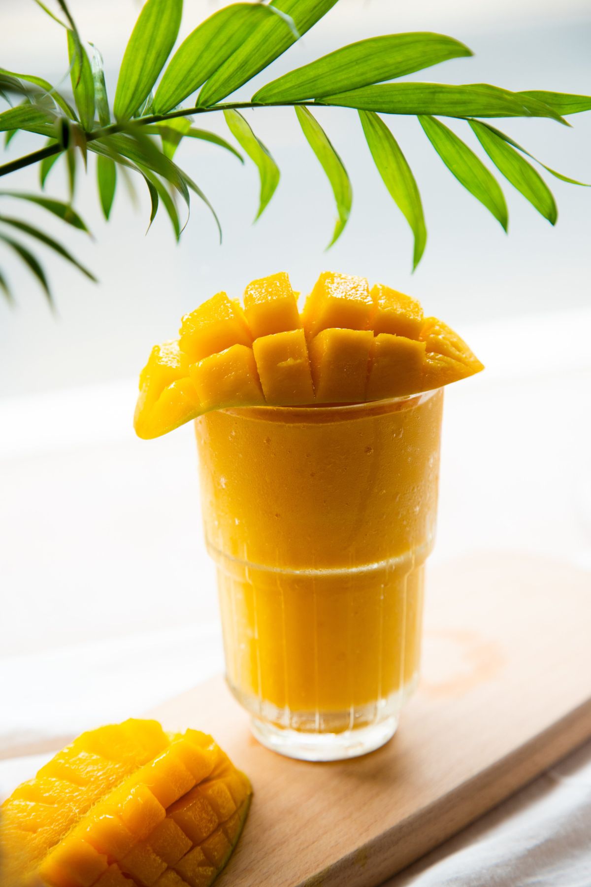 A mango smoothie topped with fresh mango; illustrative stock photograph