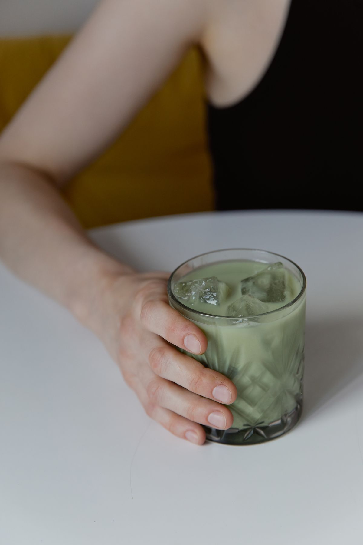 An iced matcha drink held over a white table