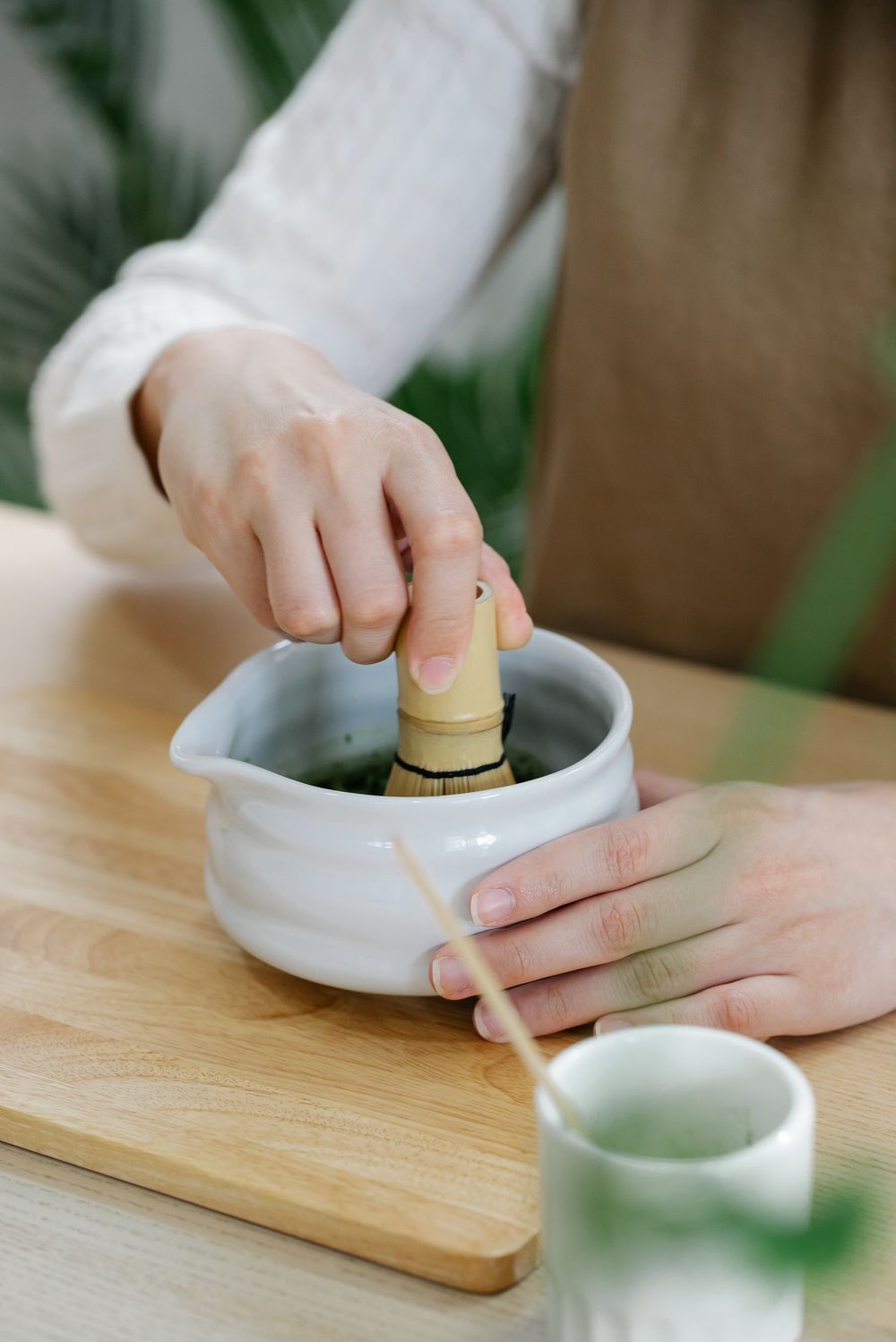 Hands whisking matcha in a ceramic bowl